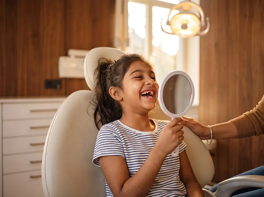 A happy child looking at her smile in a mirror